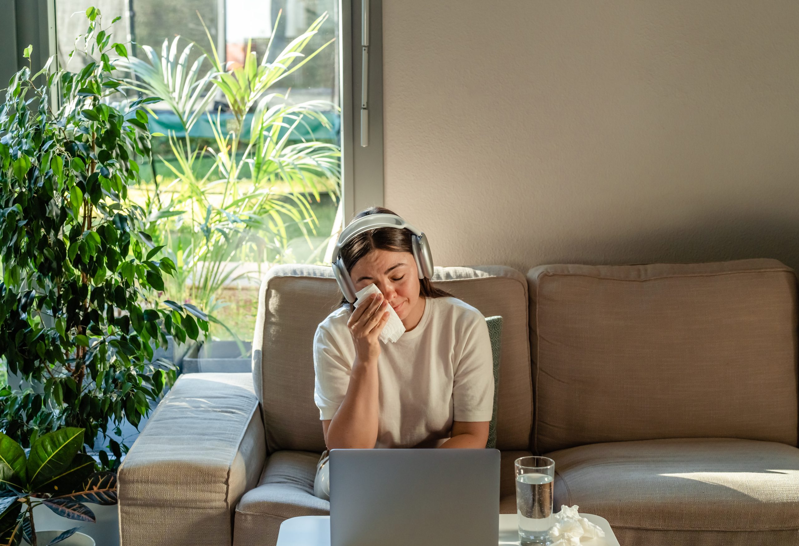 Junge Frau sitzt mit Taschentuch vor Laptop und weint