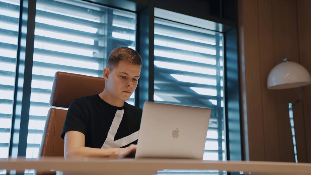 Jürgen Schroll sitzt am Schreibtisch und arbeitet am Laptop.