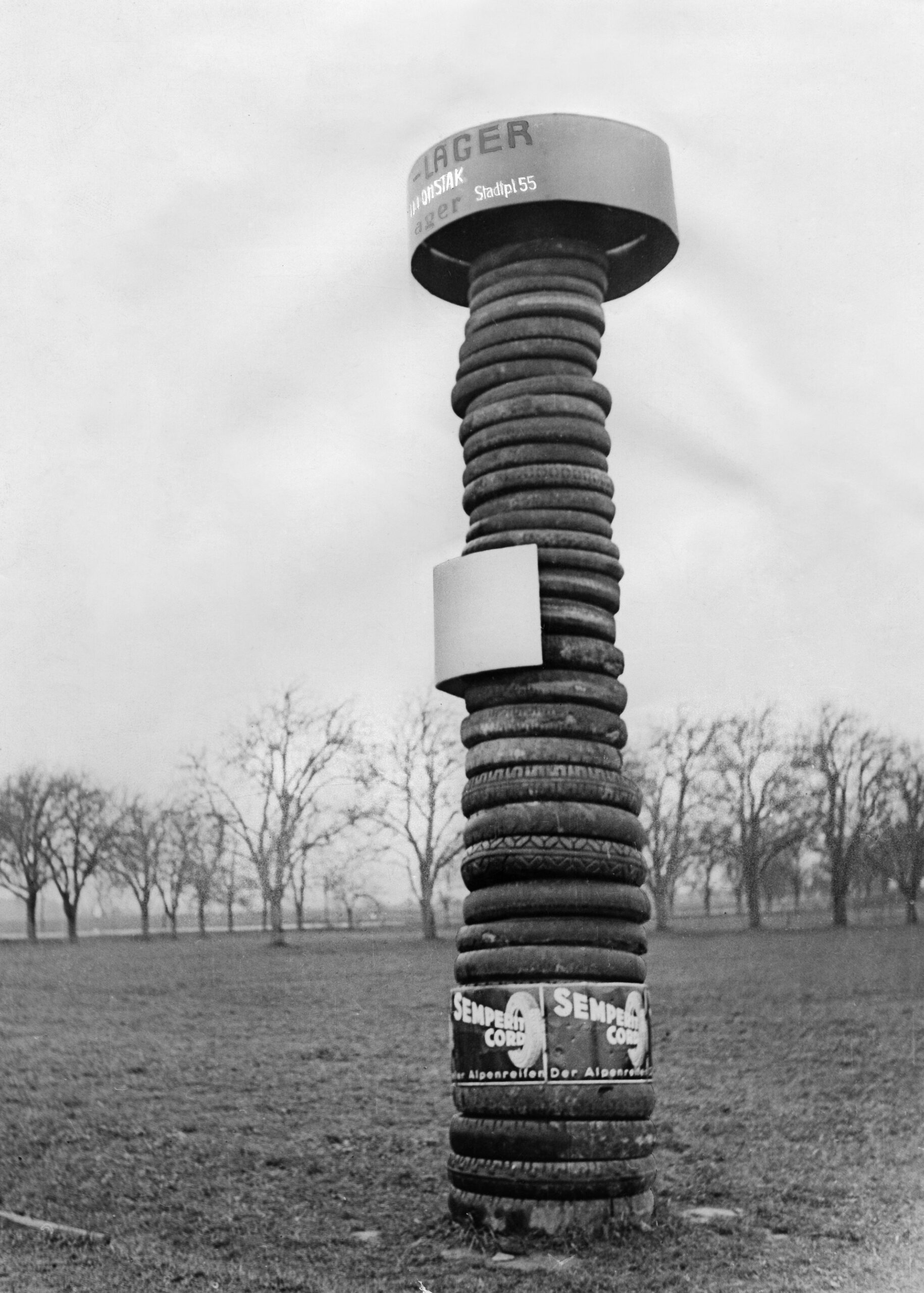 Reifenturm von Semperit in schwarz-weiß fotografiert. Dahinter befinden sich Bäume