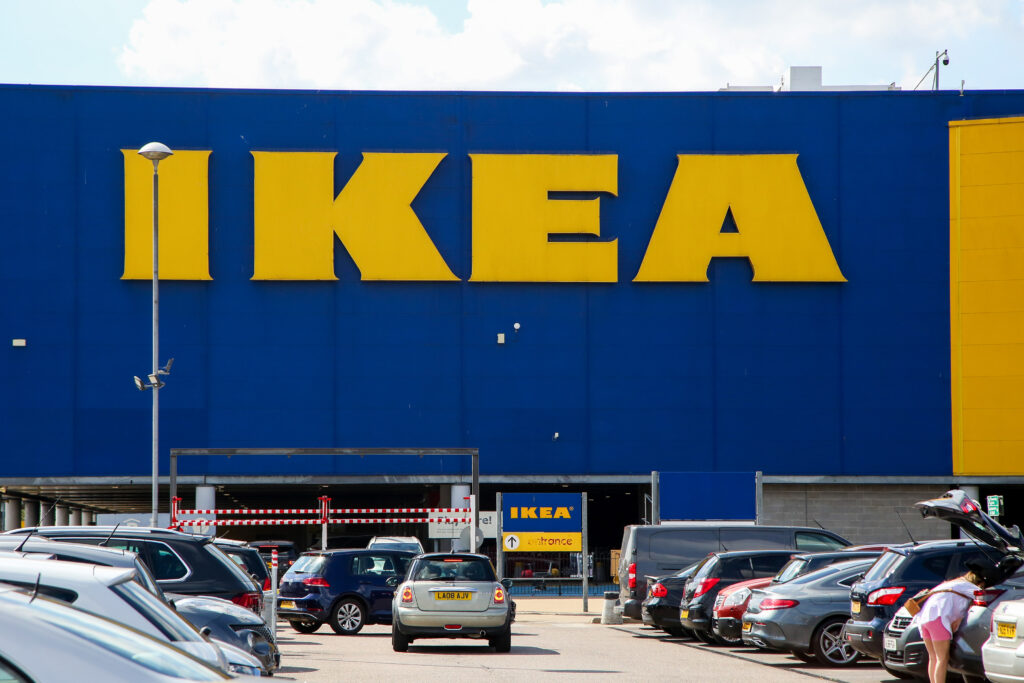 Logo von IKEA auf einem Einrichtungshaus. Davor viele Autos