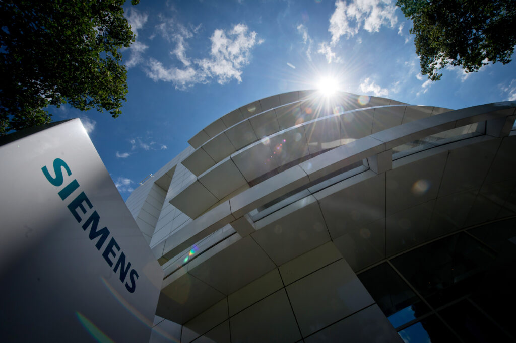 Logo von Siemens auf der linken Seite und Blick von unten fotografiert auf ein Bürogebäude