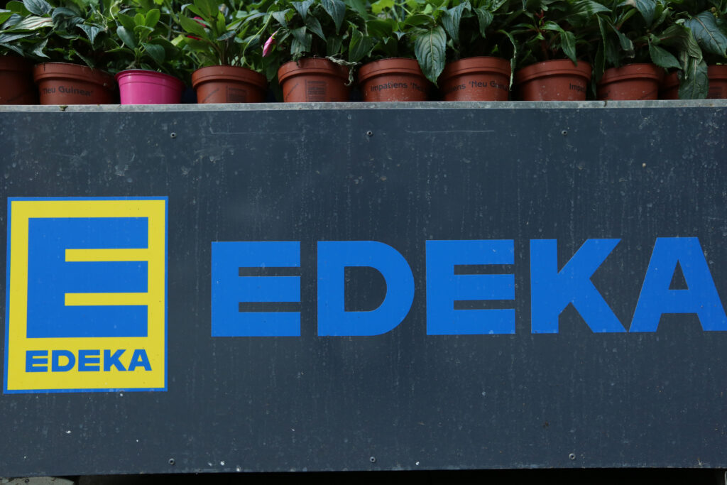 Logo von EDEKA darüber einige Blumentöpfe