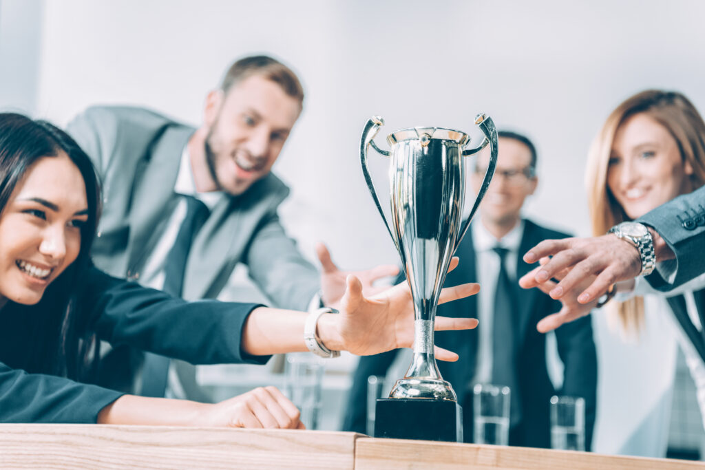 Vier Menschen unscharf aufgenommen stürzen sich auf einen Pokal, der auf einem Tisch steht