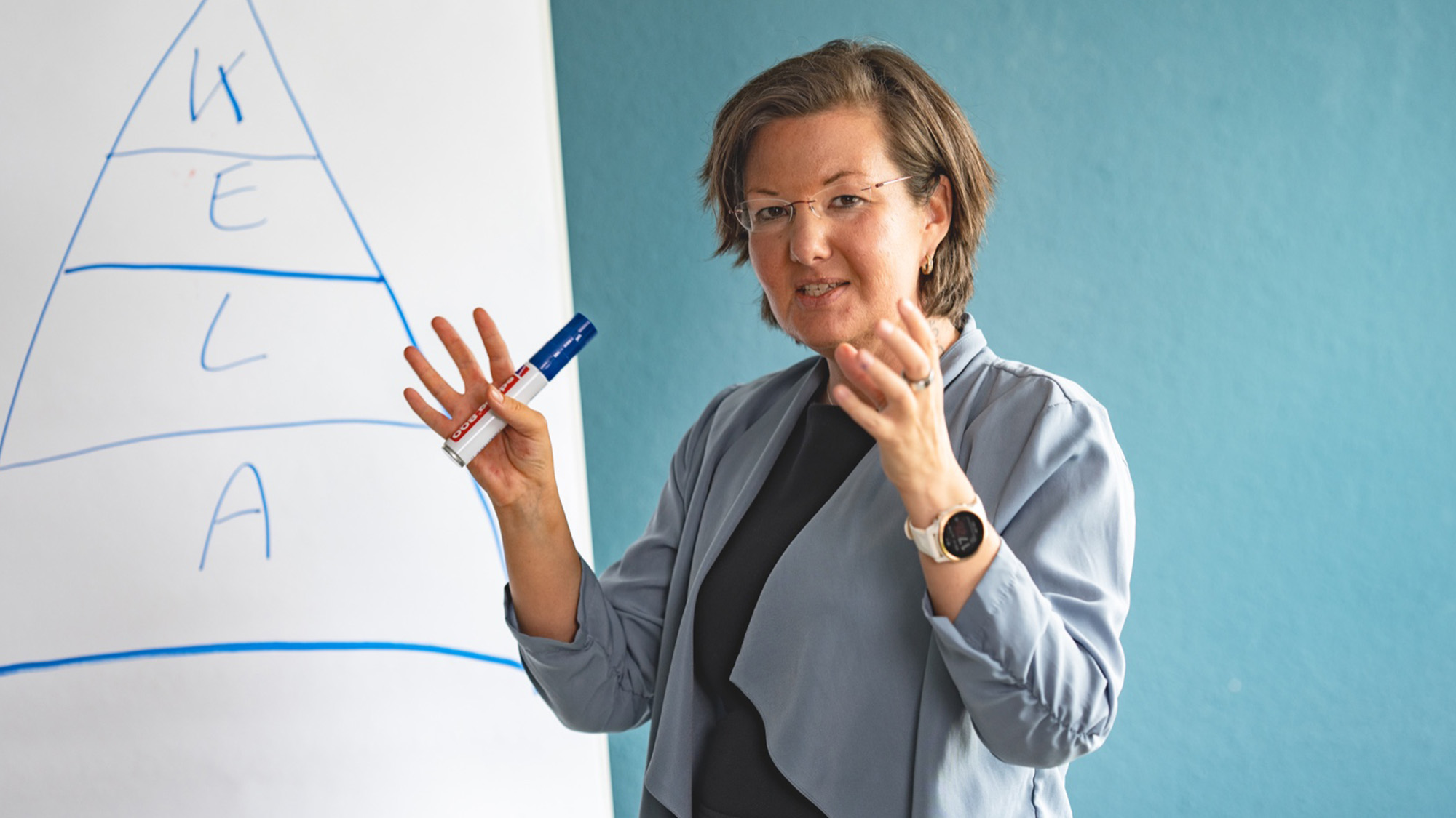 Franziska Gostner gestikuliert vor einem Flipchart stehend und mit einem Stift in der rechten Hand