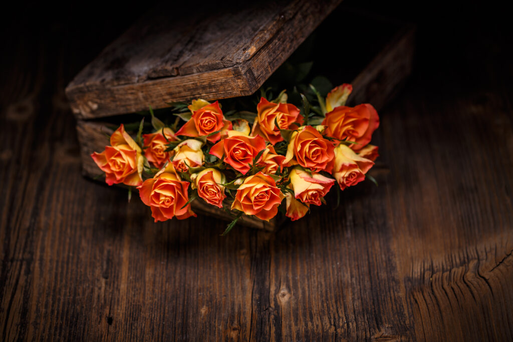 orange Rosen auf einem Holztisch in einer Holzkiste