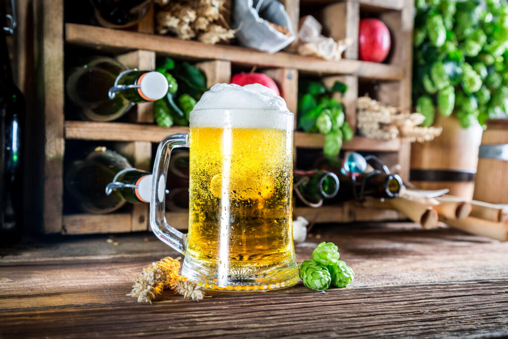 Bier mit Schaum in einem Glas vor einem Regal mit Flaschen