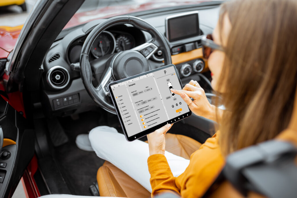 Frau sitzt mit einem Tablet das Autosoftware zeigt in einem Auto