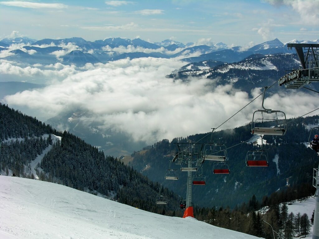 Ein Skipass hängt an einer Winterjacke vor einer verschneiten Piste, während die Skipass-Preise 2026/2027 in Südtirol steigen – Foto: aszak / Pixabay