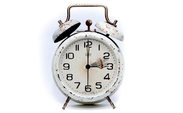 Ein analoger Wecker auf einem Nachttisch symbolisiert die Zeitumstellung im Oktober, bei der die Uhr eine Stunde zurückgestellt wird – Foto: PIRO4D / Pixabay